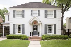 Modern gray house numbers and lush green plants complete a cottage beach house exterior. White House Gray Shutters Transitional Home Exterior Domino Magazine
