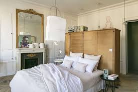 A small attic parisian bedroom with artworks, a comfy bed, lamps and stucco for decorating the walls. Decorate Your Home Like A Parisian With These Key Design Principles