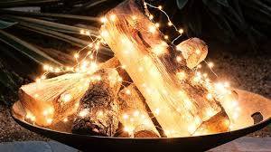 Fire Without The Flame Keep A Firepit Glowing All Season With Copper Wire Lights Loosely Draped Over A Pile Holiday Lights Outdoor Patio Lighting Diy Patio