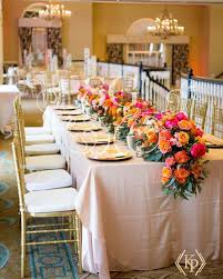 A Lush Floral Table Runner In Shades Of Fuchsia And Orange Adds A Vibrant Contrast To An Ivory And Gold Tab Floral Table Runner Gold Chiavari Chairs Gold Table