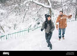 Happy Young Couple in Winter . Family Outdoors. man and woman looking  upwards and laughing. Love, fun, season and people - walking in winter  park. He is snowballing Stock Photo - Alamy