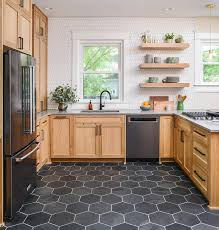 The white tile backsplash and gray cork flooring add layers of neutrals. Black Hexagon Floor Tiles With Honey Stained Cabinetry Transitional Kitchen