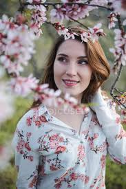 The winters aren't as harsh, and the temperatures aren't as cold, so you can grow more fruits here. View Through Twigs Of Blooming Fruit Tree Of Attractive Cheerful Lady Looking Away In Garden Between Hills Flowers Leisure Stock Photo 251671302