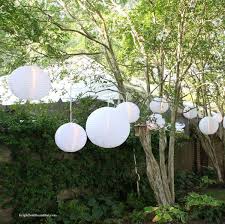 Tree lights hanging decor ideas lighting trees and bushes so they glow from the inside out is just the first step in our tree makeover for spring. Outdoor White Lanterns Outdoor Party Ideas White Party Decorations Summer Outdoor Party Outdoor Parties