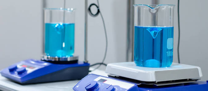 Magnetic stirrer hotplates mixing blue solutions in laboratory beakers