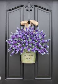 A white floral wreath hangs on the door while two green pots are in charge of the ornamental plants. Front Door Decor Front Door Decorating Ideas