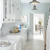 Low back rattan stools at a glossy blue kitchen island topped with a white quartz countertop. 1