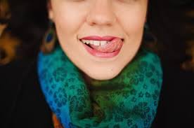Little girl looking at the camera with her tongue sticking out to one side  of her mouth. by Marcela Limon. Photo stock