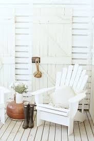 A Beach Cottage Look With An Old Rustic Door And An Adirondack Chair In All White Coastal Cottage Decorating Beach House Interior Beach Cottage Decor