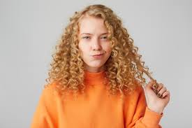 My curls cannot live without these essentials. Free Photo Cute Curly Haired Blonde With Blue Eyes Suspiciously Looking At The Front Holds A Strand Of Hair Thinking About Something