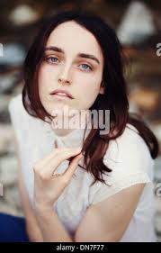 Young woman wearing long brown cardigan, black pleated skirt and standing  in an office Stock Photo