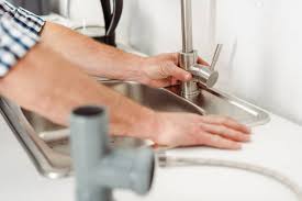 A dripping faucet isn't just annoying; Selective Focus Of Plumber Fixing Kitchen Faucet Near Pipes On Worktop Cropped Repairing Stock Photo 386968010