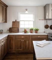 Medium Stained Cabinetry With White Tongue And Groove Backsplash Brass Cup Pull Hardware Farmhouse S Home Kitchens Stained Kitchen Cabinets Kitchen Remodel