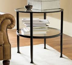 A round stone accent table is styled with white and black stacked books, a clear glass flower vase, and a framed art piece on a gold stand. Pottery Barn Living Room Sale Save Up To 30 On Coffee Tables Side Tables Rugs Pool Tables Drapes And More Candie Anderson