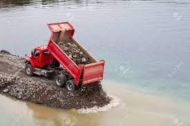 Location of the excavation ( in open area/plot excavation works could be now multiply the number of truck loads by the amount of time for one truck load and you will come. Red Dump Truck Dumping Load Of Soil Into Water Building Seawall Stock Photo Picture And Royalty Free Image Image 50005352