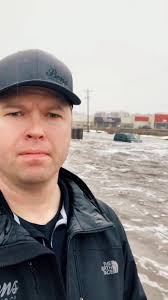 Guy Standing in His Trailer As Rhe Flood Waters Go by