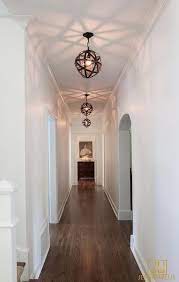 Long White Hallway Finished With An Arched Doorway Is Illuminated By Armillary White Hallway Hallway Pendant Lighting Long Hallway