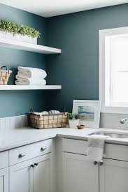 This blogger installed a pegboard that serves as storage for all of her tools and dirty. White Floating Shelves On Blue Laundry Room Walls Transitional Laundry Room