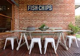 Industrial Style Outdoor Table Area Brick Wall With Vintage Sign Outdoor Dining Spaces Outdoor Dining Decorating On A Budget