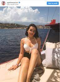 Vêtue d'une culotte taille haute noire et d'un haut de maillot de bain blanc, elle prend la pose sur un bateau. Agathe Auproux En Bikini