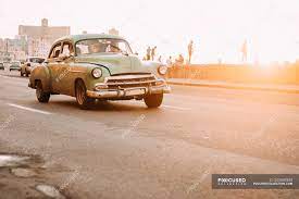 Avoid tapping your foot against the gas pedal when this comes on. Vintage Car Driving Down Road At Sunset Cuba Auto Tropical Stock Photo 205549334