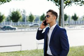 Mężczyzna w brązowym garniturze (ang. Przystojny Mezczyzna W Garniturze Spacery Po Ulicy W Sloneczny Dzien I Rozmowy Na Jego Smartphone Darmowe Zdjecie