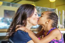 Mother and daughter kissing in cafe - Royalty-free Stock Photo | Dissolve