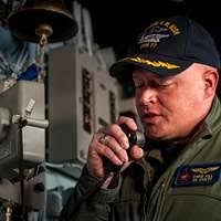 Capt. Chris Hill, executive officer of the aircraft carrier USS George H.W.  Bush (CVN 77), addresses the ship over the 1MC
