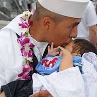 Storekeeper 3rd Class Kyle Harding, assigned to Navy Customs Battalion  (NCB) Romeo, holds his three-month-old son for the first time after NCB  Romeo's homecoming.