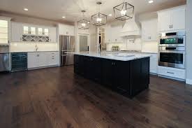 Dark brown wood floor kitchen. Dark Brown Hickory Hardwood In White Kitchen With White Tile Backsplash And Black Kitchen Island Black Kitchen Island White Tile Backsplash Black Kitchens