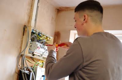 Electrician fitting a dimmer switch faceplate on living room wall