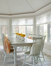 Yellow And Gray Sunroom Features A Gray Roll Arm Sofa Illuminated By Suzanne Kasler Quatrefoil Floo Windsor Dining Chairs Sunroom Dining Farmhouse Dining Table