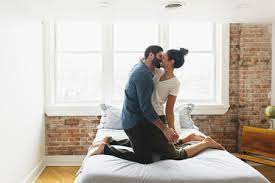 Getting a bed and lying there with your partner is not enough. Romantic Couple Kissing While Kneeling On Bed At Home Stockphoto