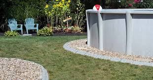 The frame and steps are made of concrete block while the grey gravels decorate the pool's surrounding. Use Stone Edge Decorative Edging For Around Your Above Ground Pool It Is Chlorine And Wate Landscaping Around Pool Above Ground Pool Landscaping Backyard Pool
