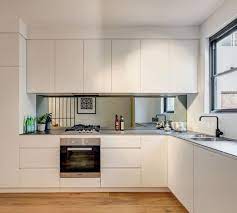 For a sleek and modern appearance, the addition of a glass tile backsplash to the kitchen or bathroom is a wonderful way to upgrade a room's overall aesthetics. Modern Sleek Line Kitchen With Mirror Backsplash Modern White Kitchen Cabinets Kitchen Wall Tiles Design Contemporary Kitchen Backsplash