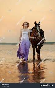 زن زیبا سوار بر اسب در غروب آفتاب در ساحل جیر جوان 1512377