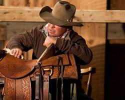 someone cleaning and conditioning a western saddle