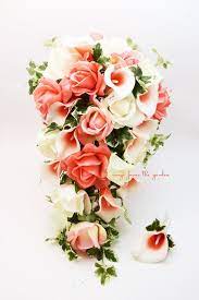 A lush wedding centerpiece of coral peonies, coral garden roses, plum branches. Cascade Bridal Bouquet Coral Picasso Callas Real Touch White And Coral Roses With Boutonniere Cascading Bridal Bouquets Bridal Bouquet Coral Bridal Bouquet