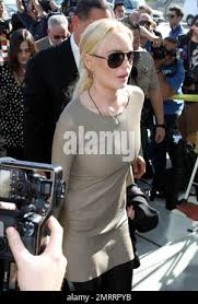 Wearing a simple beige dress, Lindsay Lohan arrives at the courthouse for a  hearing to potentially