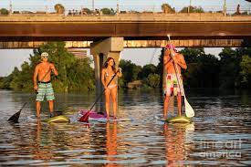 Paddle boarding is much easier than it looks, and if you want you can sit down or kneel rather than standing up on the board. A Group Of Friends Enjoy A Beautiful Summer S Day While On Stand Up Paddle Boards Sup On Lady Bird Lake In Austin Texas Photograph By Herronstock Prints