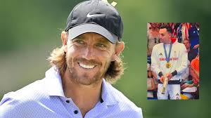 Tommy Fleetwood reacts to British swimmer James Guy taking a golf stroke  with his Olympic trophy