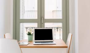 A small home office desk placed near a window with tidy organization