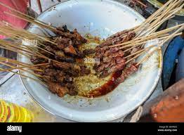 Freshly grilled satay kambing in a white enamel bowl with a stainless steel  rim, from which delicate sos flows.Chicken satay is grilled chicken skewer  Stock Photo - Alamy