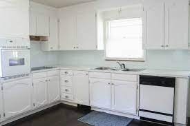 The kitchen features white cabinets, black countertops, black hardware, matte black faucet, black sink, and wood accents. Painting Oak Cabinets White An Amazing Transformation Lovely Etc