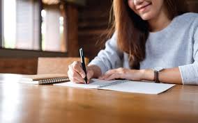 Imagem de close de uma mulher escrevendo em um caderno em branco na mesa de  madeira | Foto Premium