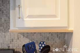 This amazing coastal kitchen makeover has white kitchen cabinets, a seaglass blue coastal backsplash, mixed metals and weathered oak floors. Easy And Inexpensive Cabinet Updates The 15 Minute Fix Adding Trim To The Bottom Of Cabinets The Rozy Home