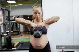 Lifting heavy items when you're pregnant can be risky and challenging. Pregnant Woman Lifting Kettle Bell In Gym Athletic Exercising Stock Photo 228978202