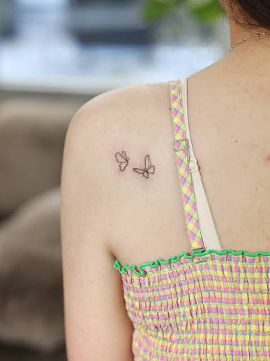 Two butterflies on the upper back. A simple line tattoo—but with double lines, the drawing feels fuller, as if each stroke carries a quiet depth. Even the smallest mini tattoo can hold