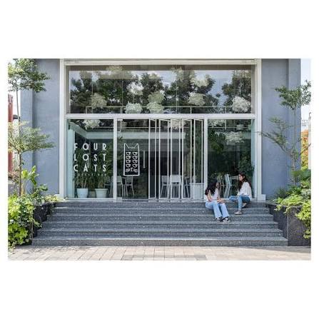 FOUR LOST CATS Bringing a touch of nature indoors, an abundance of plants  graces the café's interior and exterior, basking in the abundant natural  light filtering through the glass façade. These plants