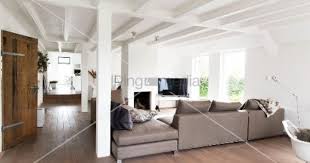 Elegante Hellgraue Sofakombination In Offenem Wohnraum Mit Landlichem Charme Weisse Holzbalkendecke Und Stutzen Offene Wohnraume Haus Und Heim Holzbalkendecke